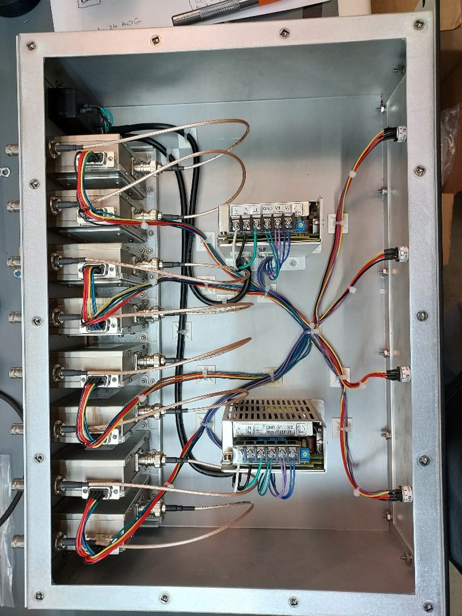 A sheet metal enclosure during box-build, with modules, dual power supplies, grounding braid and a routed multi-conductor wire harness.